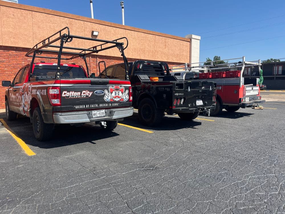Red Ford truck with Cotton City logo parked next to two other utility vehicles on a lot.