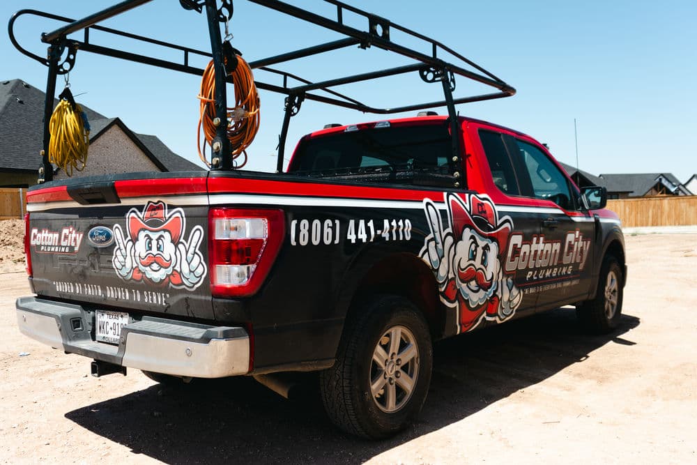 Cotton City Plumbing branded truck with logo and contact number parked in a residential area.